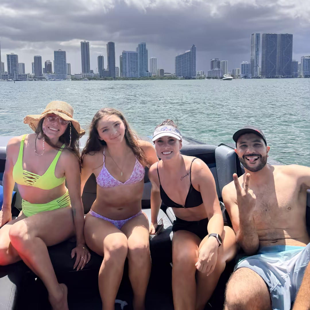 Four smiling guests on the boat with the Miami skyline behind them